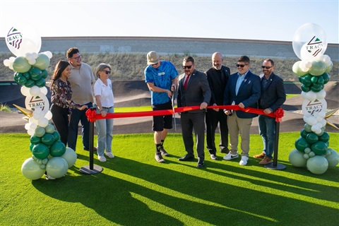 People cutting red ribbon with large scissors