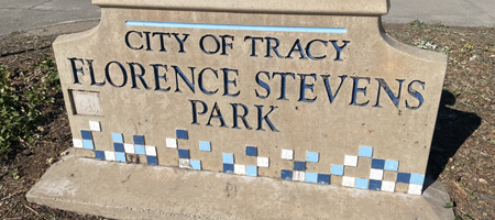 Stone sign reading ‘City of Tracy Florence Stevens Park’ with decorative blue and white tiles along the bottom.