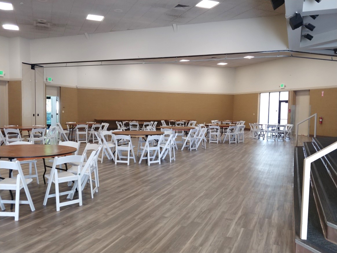 Main Tracy Community Center dining hall area with table and chairs in front of the stage