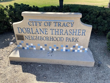 Stone entrance sign reading 'City of Tracy, Dorlane Thrasher Neighborhood Park' with a blue tile mosaic border.