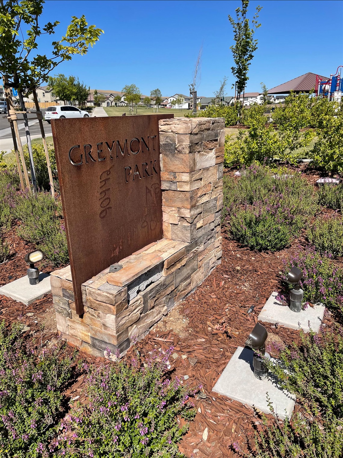 Stone and weathered steel park entrance sign displaying 