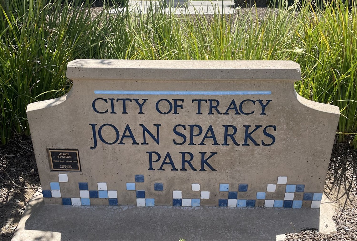 Stone entrance sign reading 'City of Tracy, Joan Sparks Park' with a blue tile mosaic border.