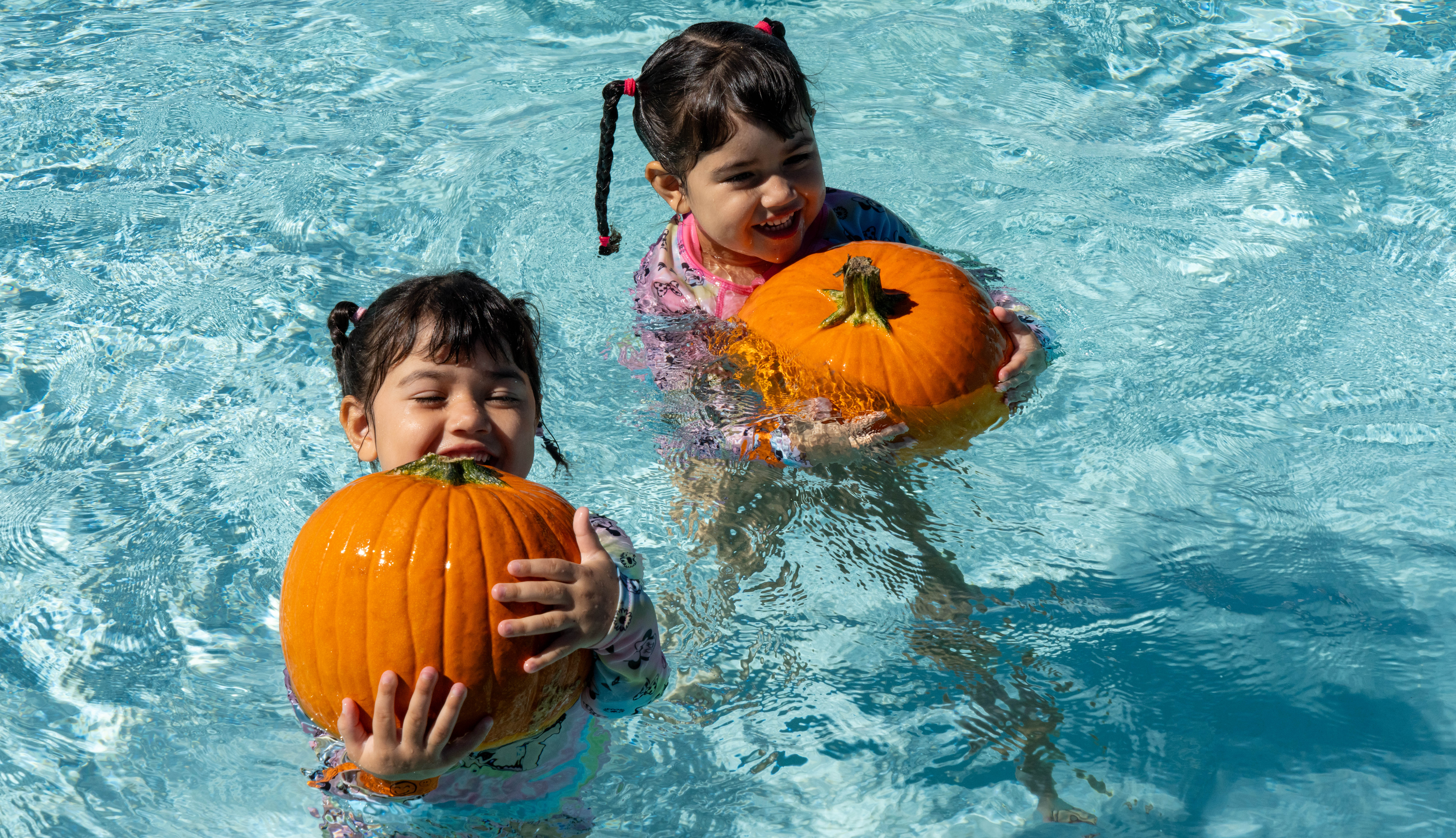 two children in pool with pumpkins